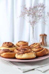 Photo of Many tasty cinnamon rolls on white table, closeup. Space for text