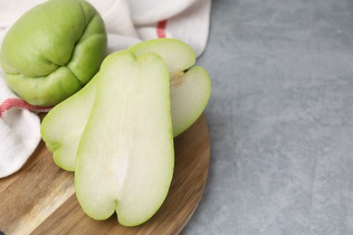 Cut and whole chayote on gray table, closeup. Space for text