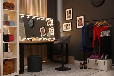 Photo of Chair, clothes rack and stylish mirror on dressing table in makeup room