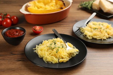 Photo of Tasty spaghetti squash with thyme and cheese served on wooden table