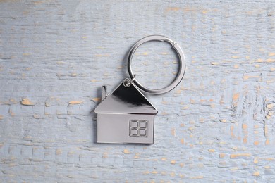 Photo of Metal keychain in shape of house on grey wooden table, top view