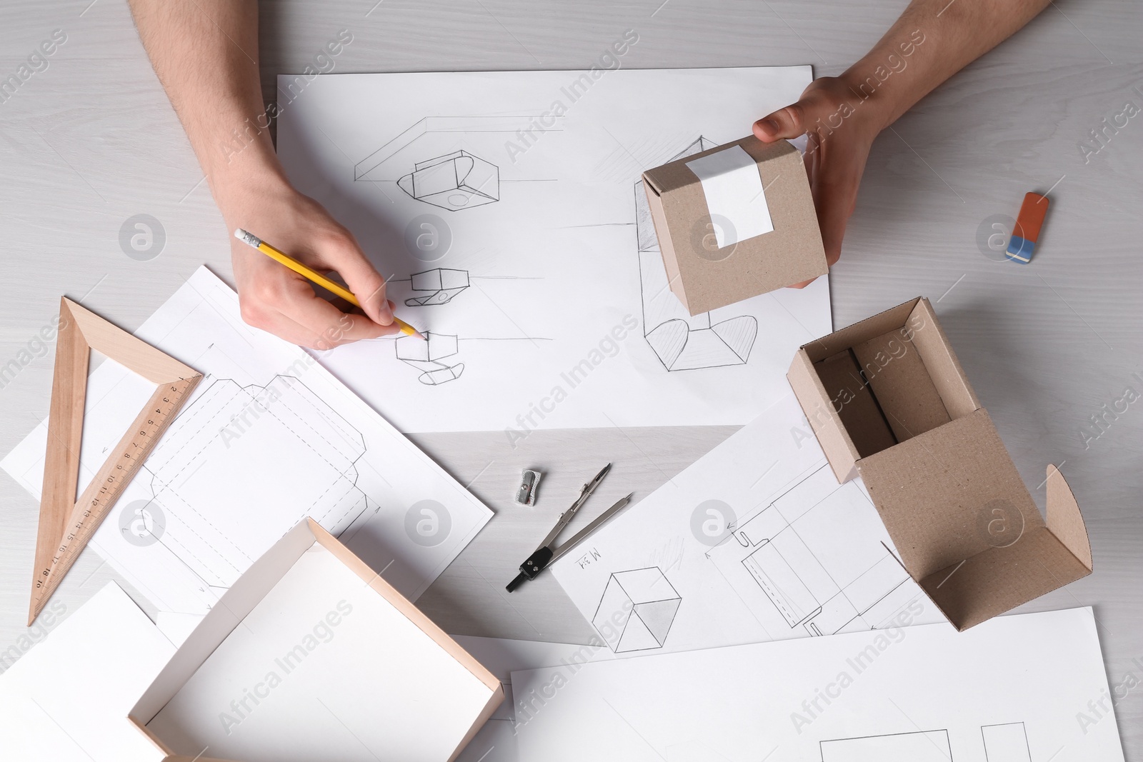 Photo of Man creating packaging design at light wooden table, top view