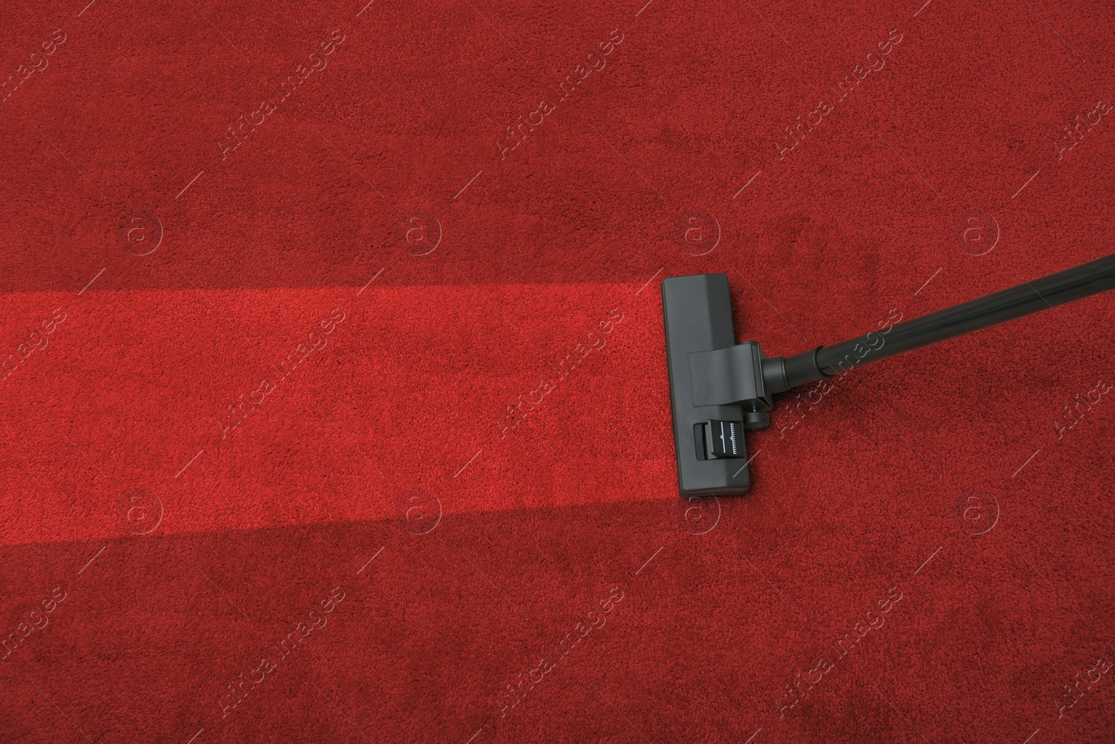 Image of Vacuuming dirty red carpet. Clean area after using device, top view