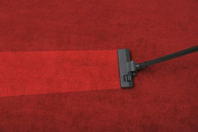 Image of Vacuuming dirty red carpet. Clean area after using device, top view