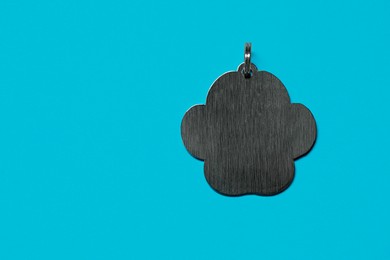 Photo of Silver pet tag with ring on light blue background, top view. Space for text