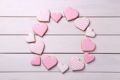 Photo of Frame of glazed heart shaped cookies on white wooden table, flat lay. Space for text