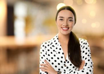 Portrait of happy woman in office. Pretty girl looking at camera and smiling on blurred background, space for text