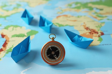 Photo of Bright paper boats and compass on world map