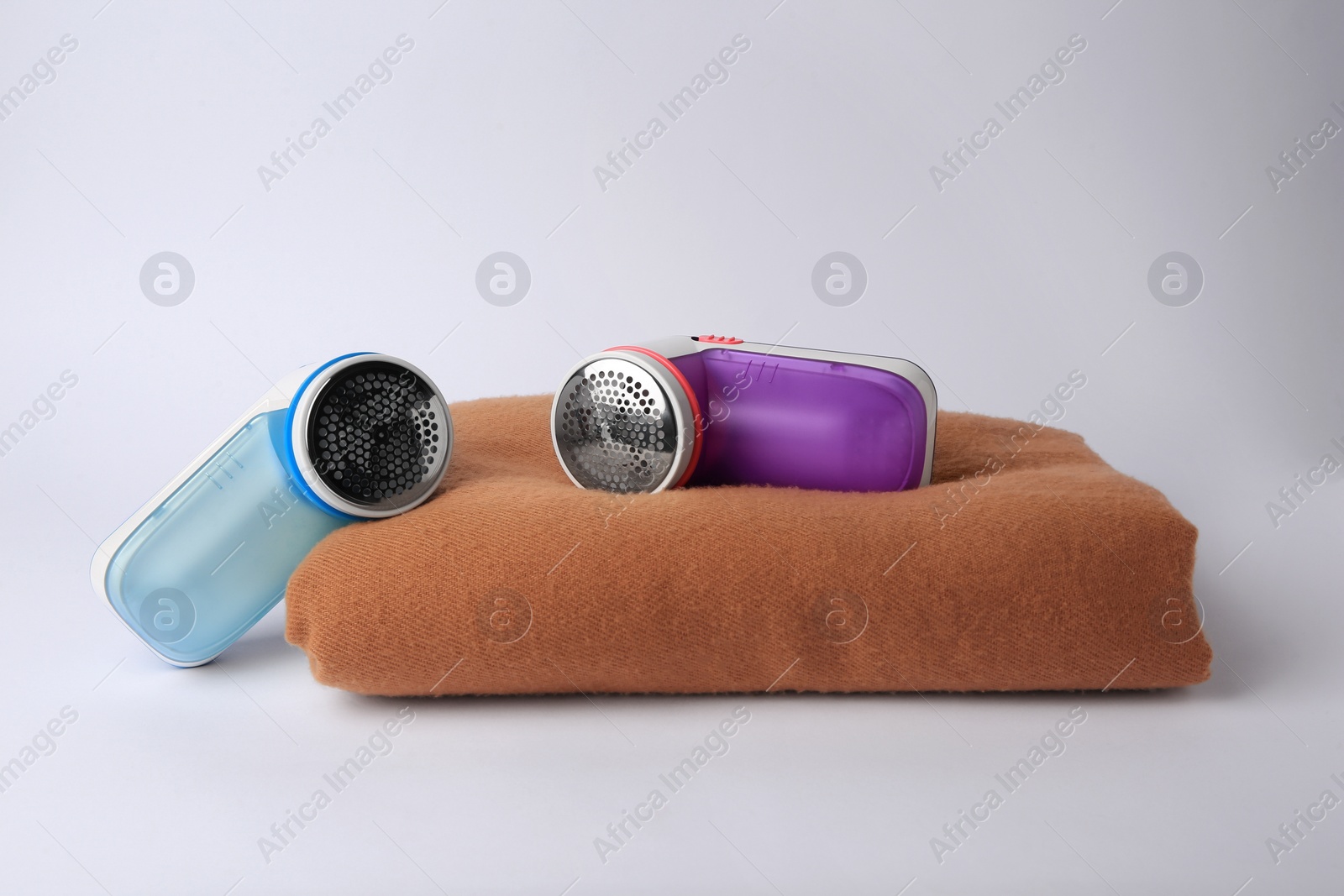 Photo of Different fabric shavers and woolen cloth with lint on white background