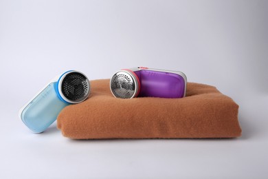Photo of Different fabric shavers and woolen cloth with lint on white background