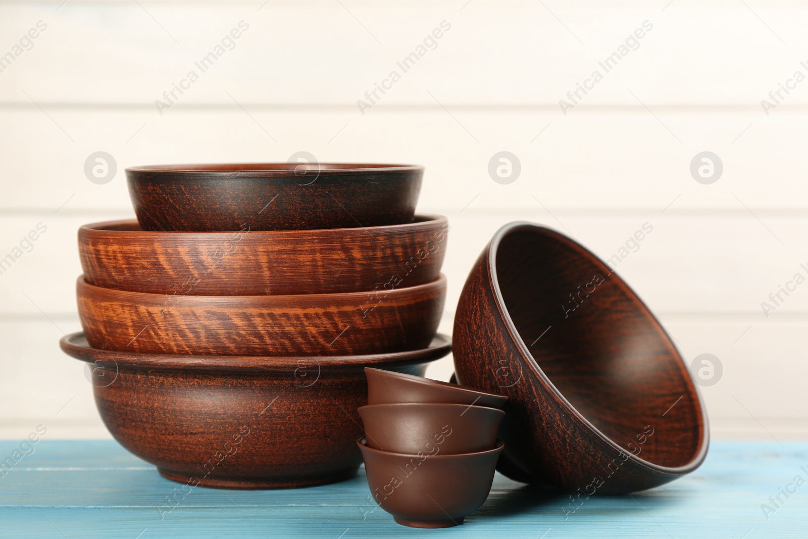 Photo of Set of clay utensils on light blue wooden table