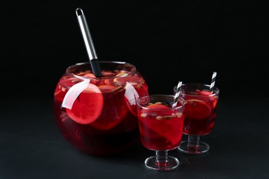 Photo of Aromatic punch drink on dark table against black background