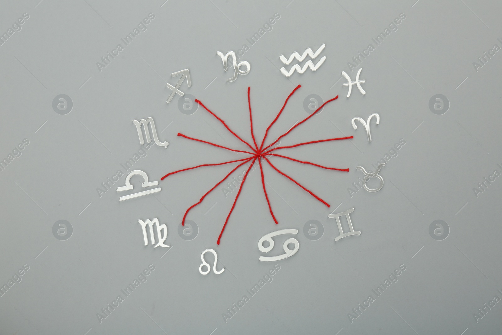 Photo of Zodiac compatibility. Signs and red threads on grey background, flat lay