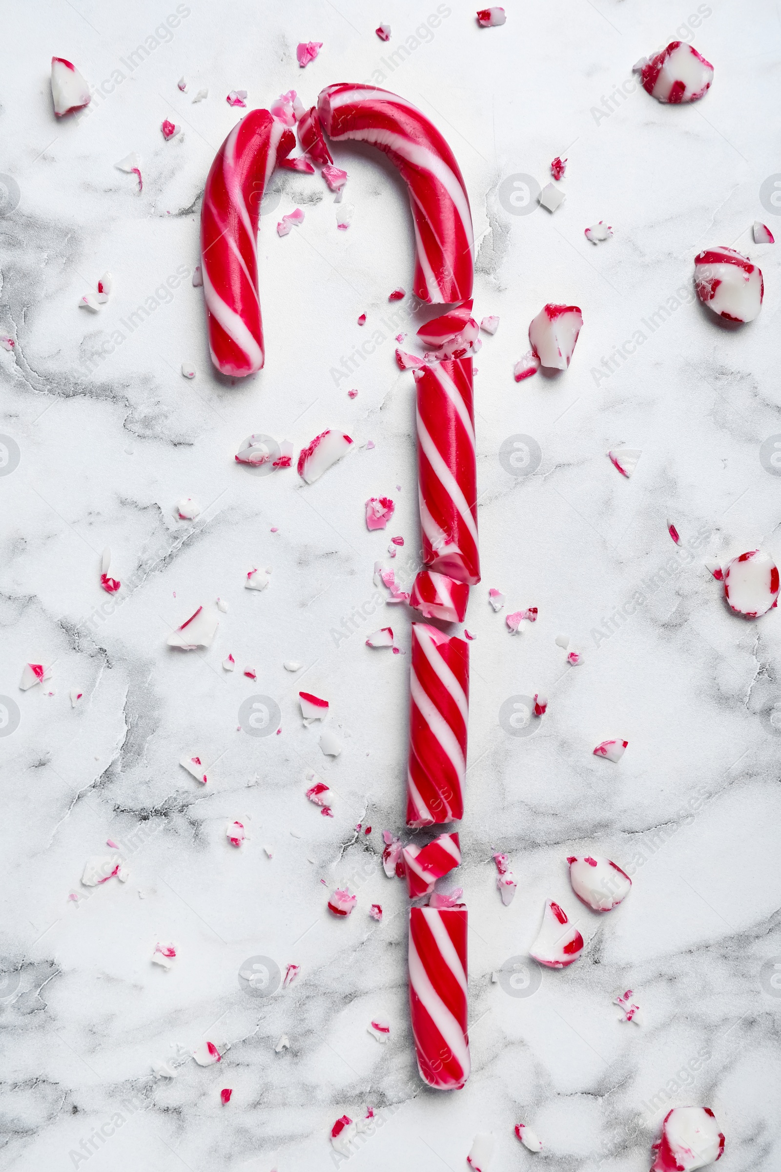 Photo of Crushed Christmas candy cane on white marble background, top view