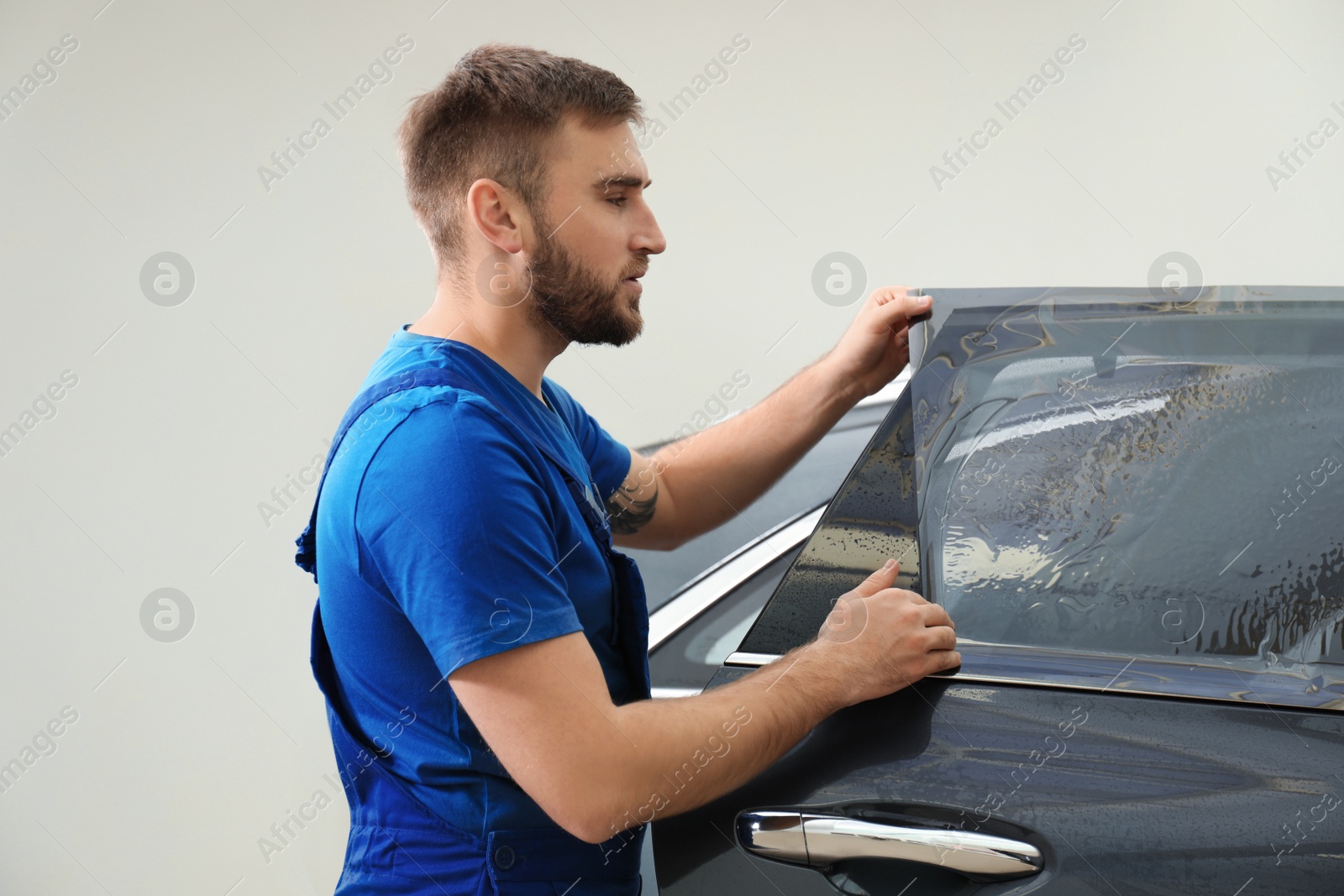 Photo of Worker tinting car window with foil in workshop