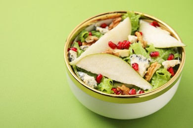 Photo of Delicious pear salad in bowl on green background, closeup