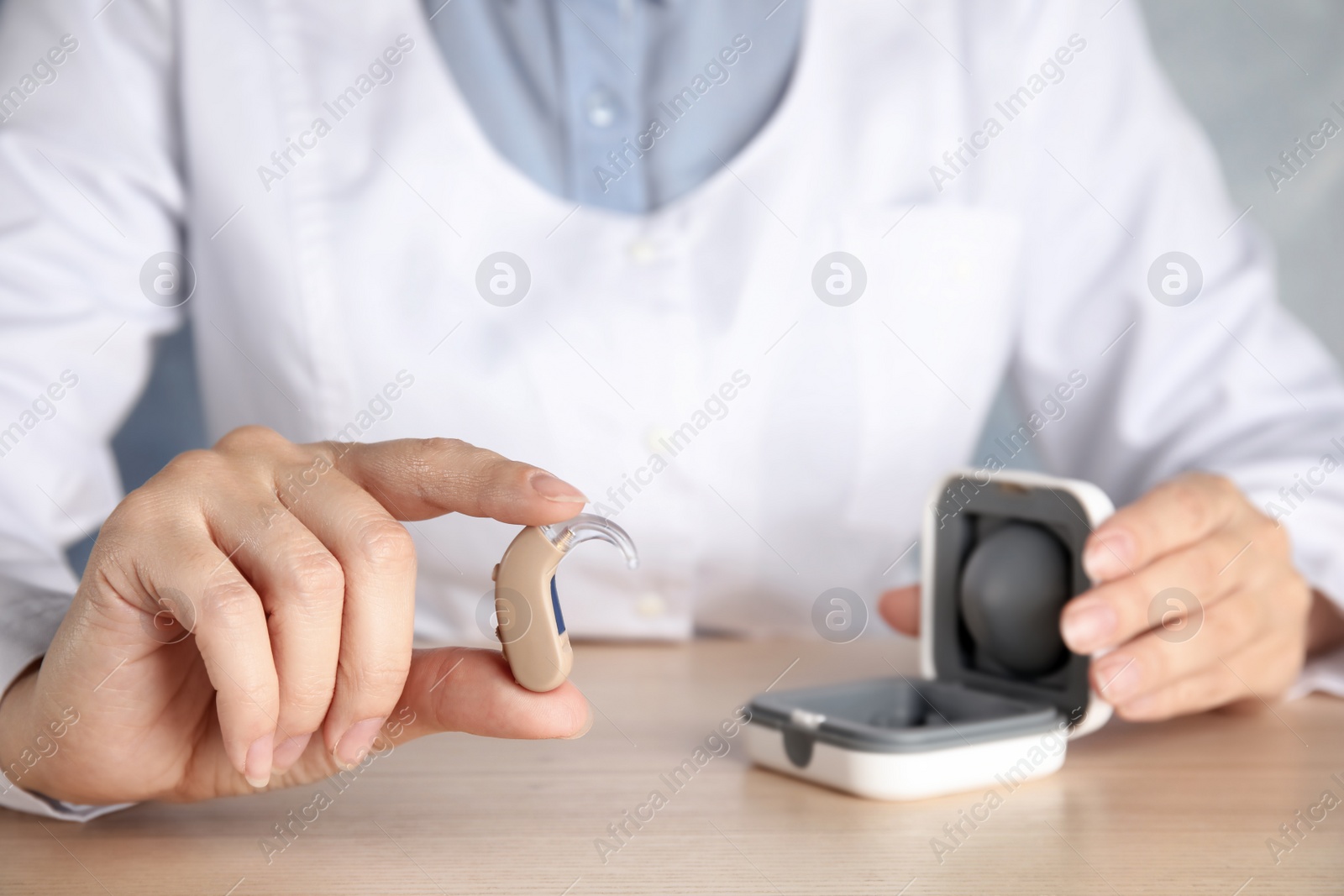 Photo of Doctor with hearing aid at table, closeup