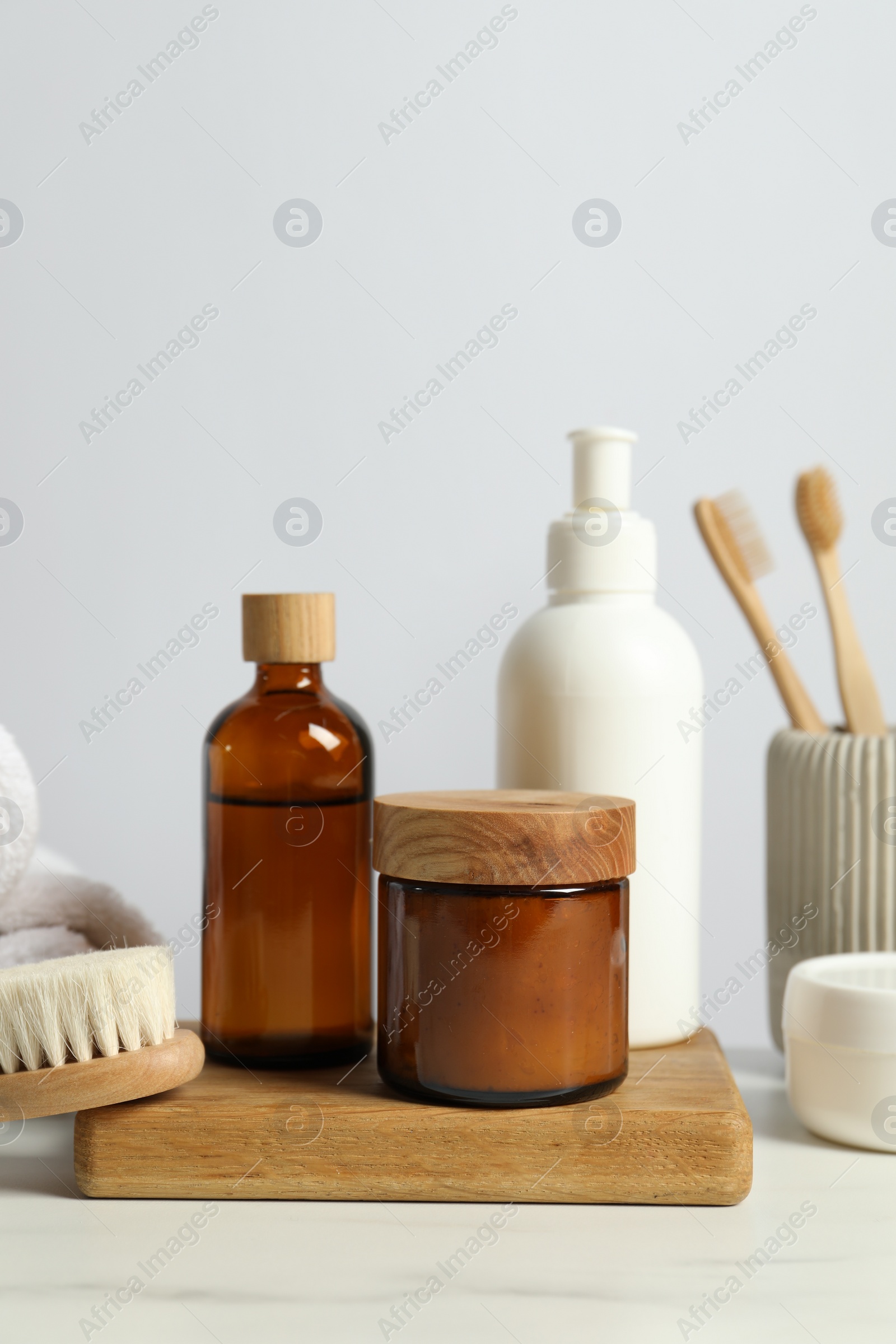 Photo of Different bath accessories and personal care products on light marble table against white wall