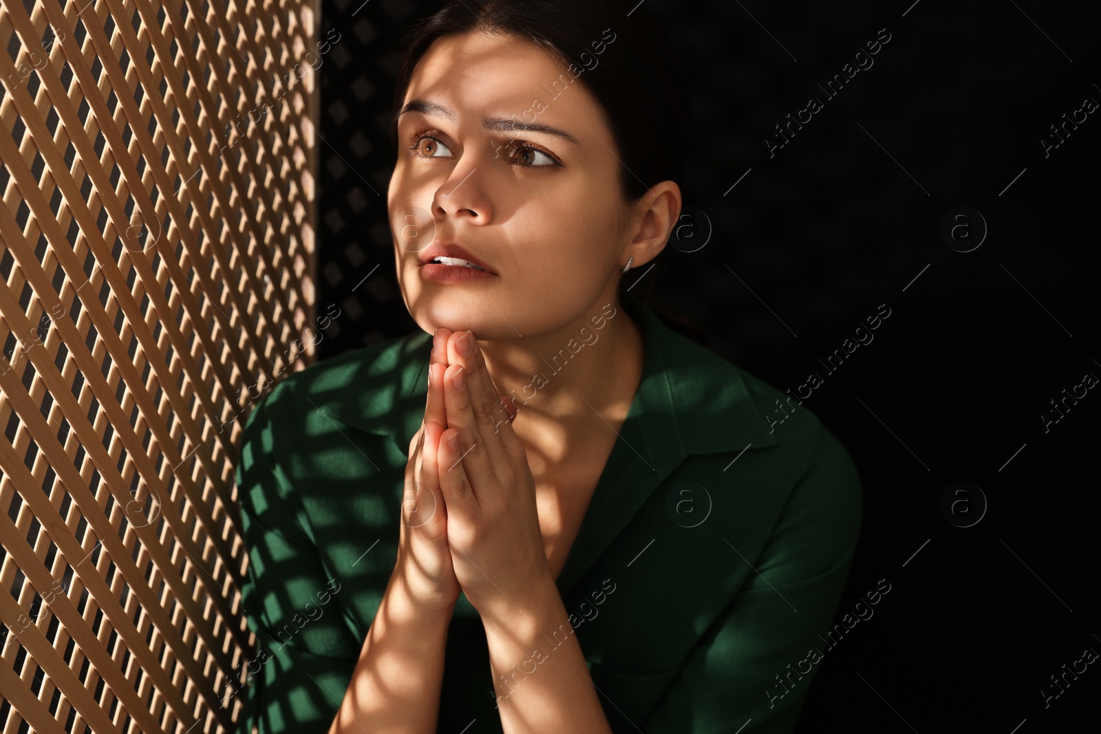 Photo of Woman praying to God during confession in booth