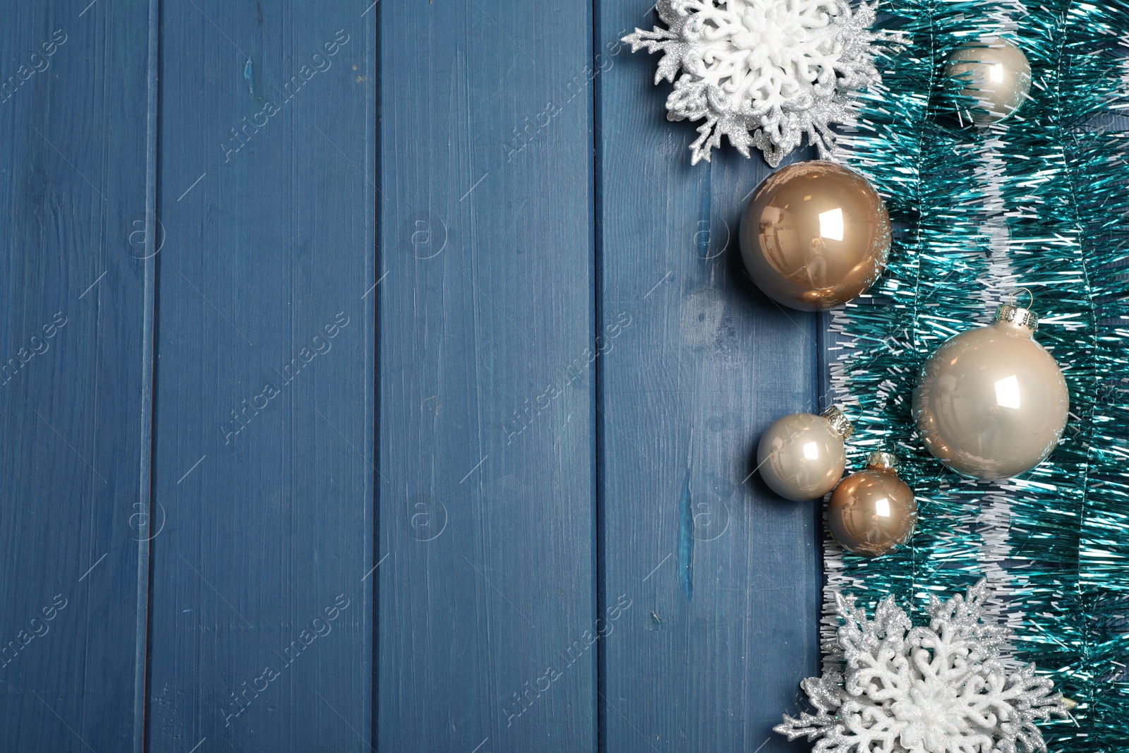 Photo of Bright tinsel and Christmas decor on light blue wooden background, flat lay. Space for text