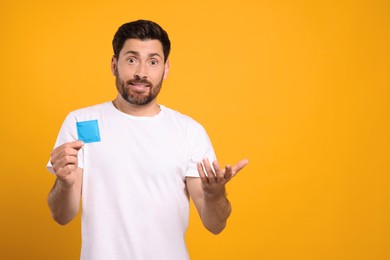 Photo of Confused man holding condom on yellow background, space for text. Safe sex
