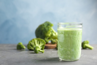 Jar with healthy detox smoothie and broccoli on table