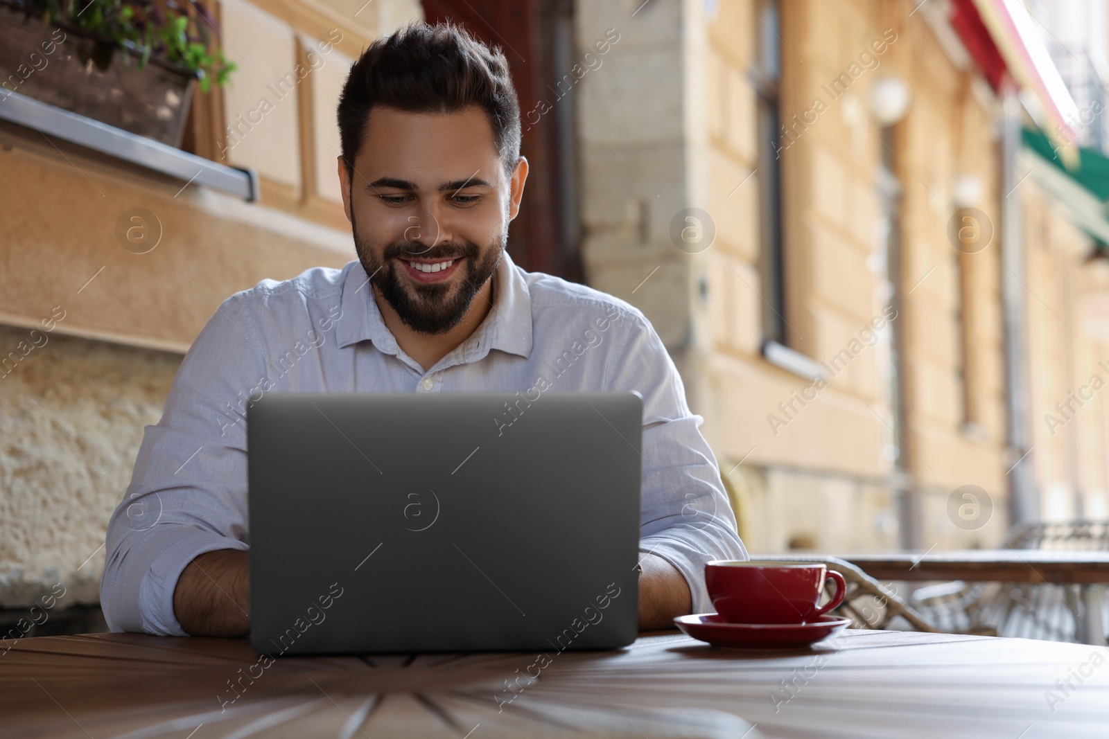 Photo of Handsome man working on laptop at table in outdoor cafe. Space for text