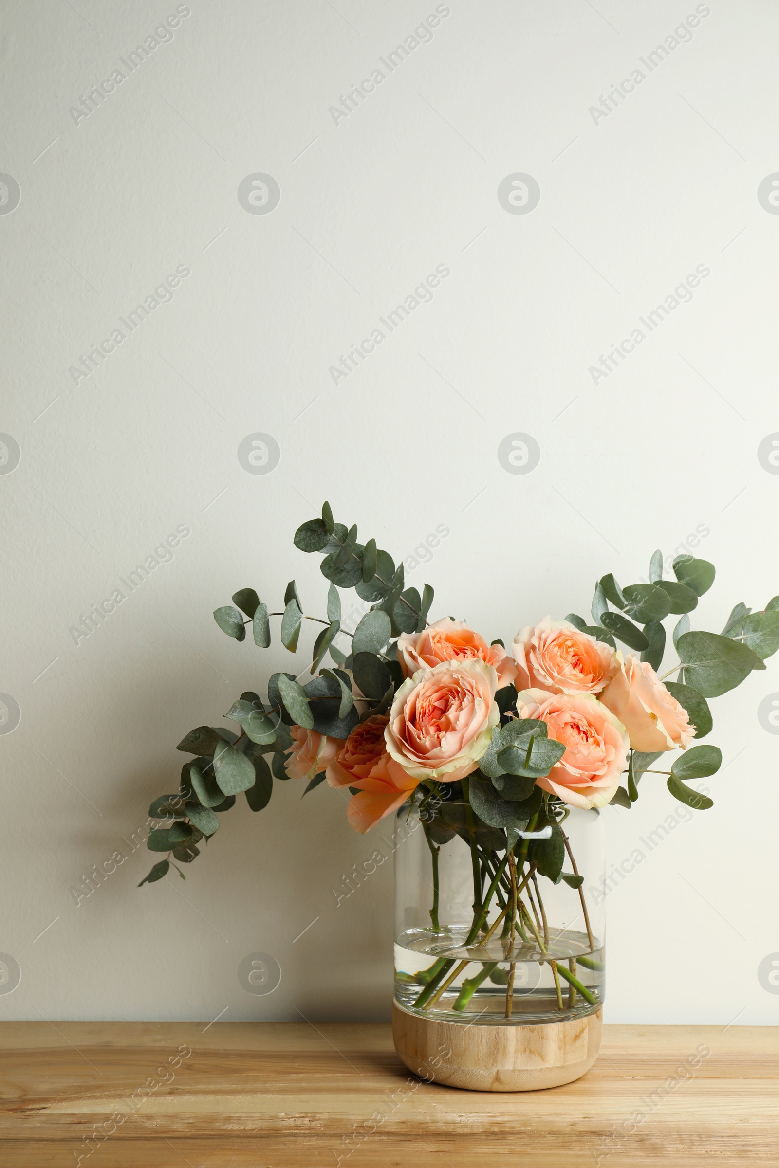 Photo of Bouquet with beautiful flowers in glass vase on wooden table against white background