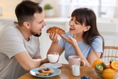 Photo of Tasty breakfast. Happy wife feeding her husband at home