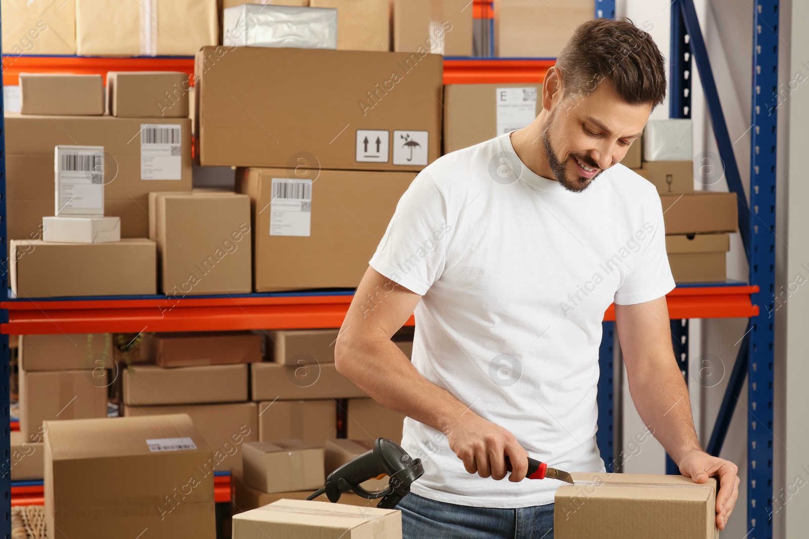 Photo of Post office worker with utility knife opening parcel indoors