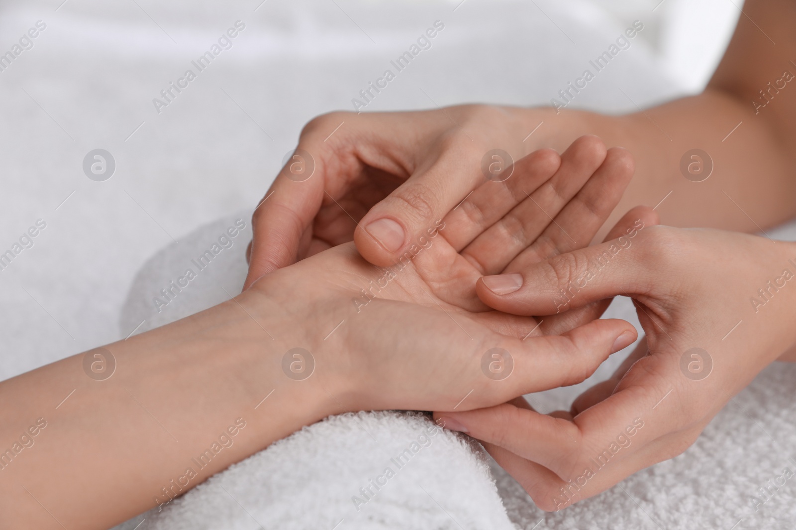 Photo of Woman receiving hand massage on soft towel, closeup