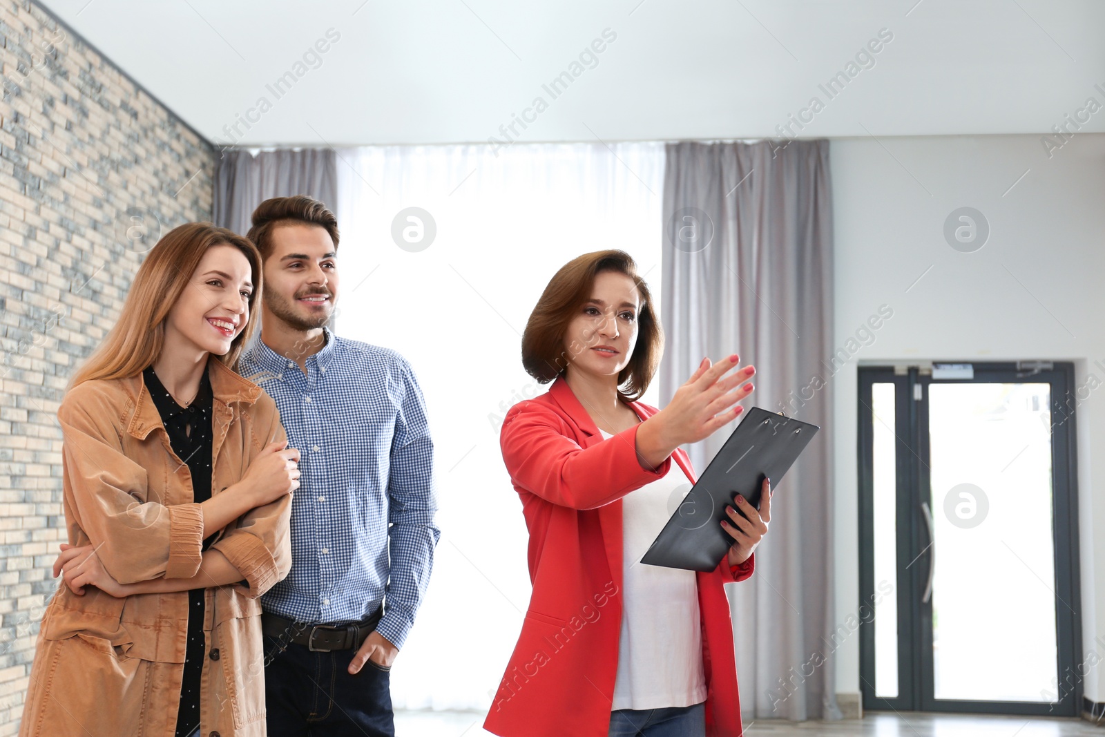 Photo of Real estate agent showing new apartment to young couple