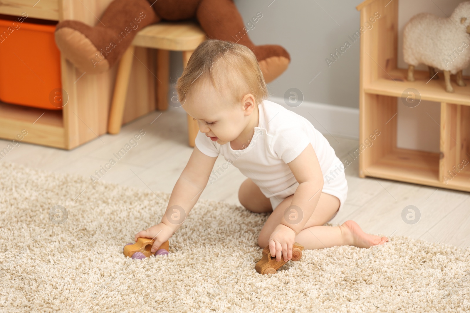 Photo of Children toys. Cute little boy playing with wooden cars on rug at home