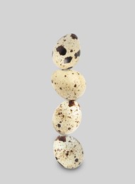 Image of Stacked speckled quail eggs on light grey background