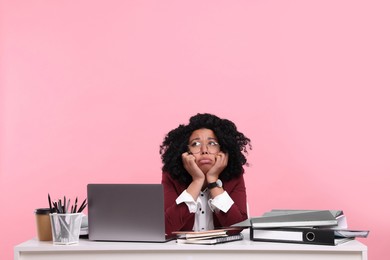 Stressful deadline. Exhausted woman sitting at white desk against pink background. Space for text
