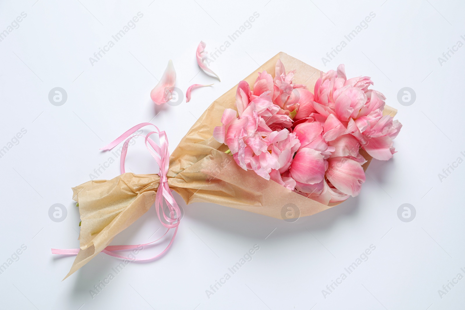 Photo of Beautiful bouquet of pink peonies wrapped in paper on white background, top view