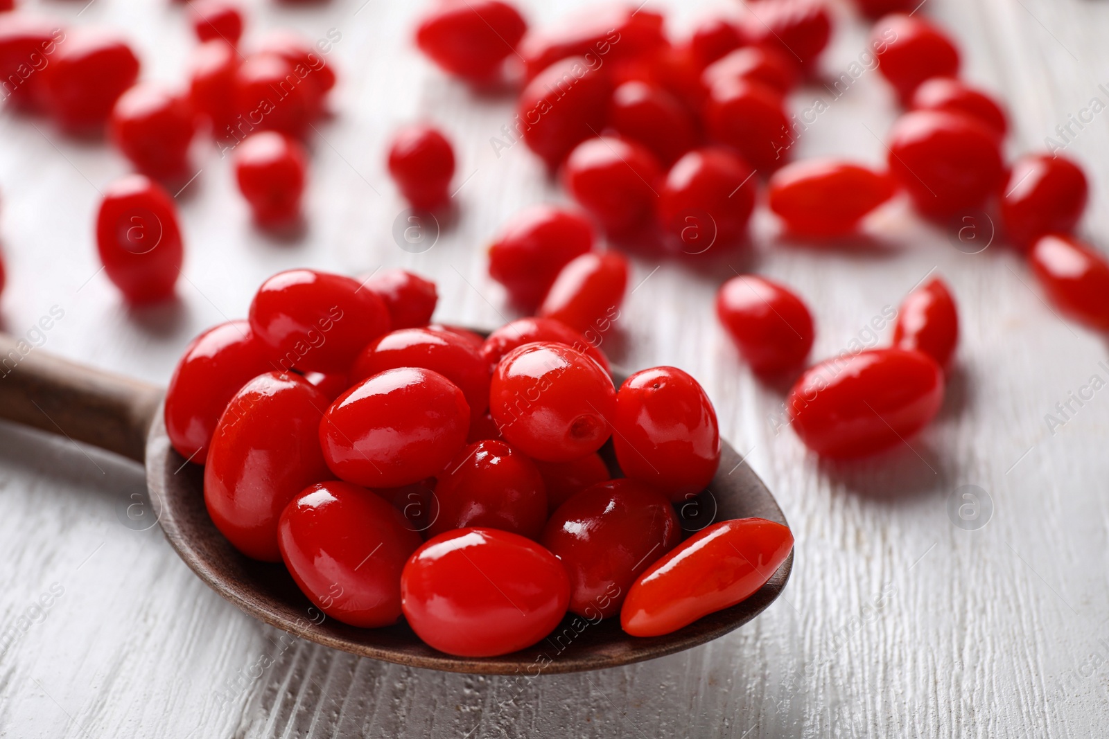 Photo of Fresh ripe goji berries in spoon on white wooden table