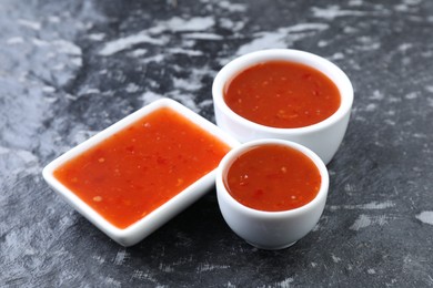 Photo of Spicy chili sauce on black textured table, closeup