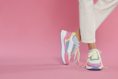 Woman wearing new stylish sneakers on pink background, closeup. Space for text