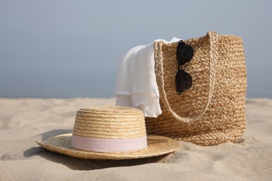 Photo of Beach bag, towel, sunglasses and hat on sandy seashore, space for text