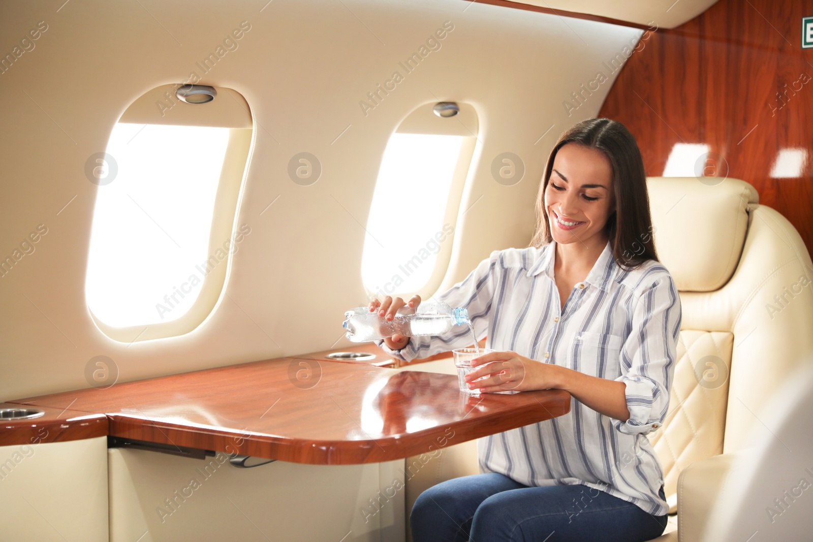 Image of Woman pouring water on plane. Comfortable flight