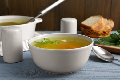 Photo of Delicious chicken bouillon with parsley on grey wooden table
