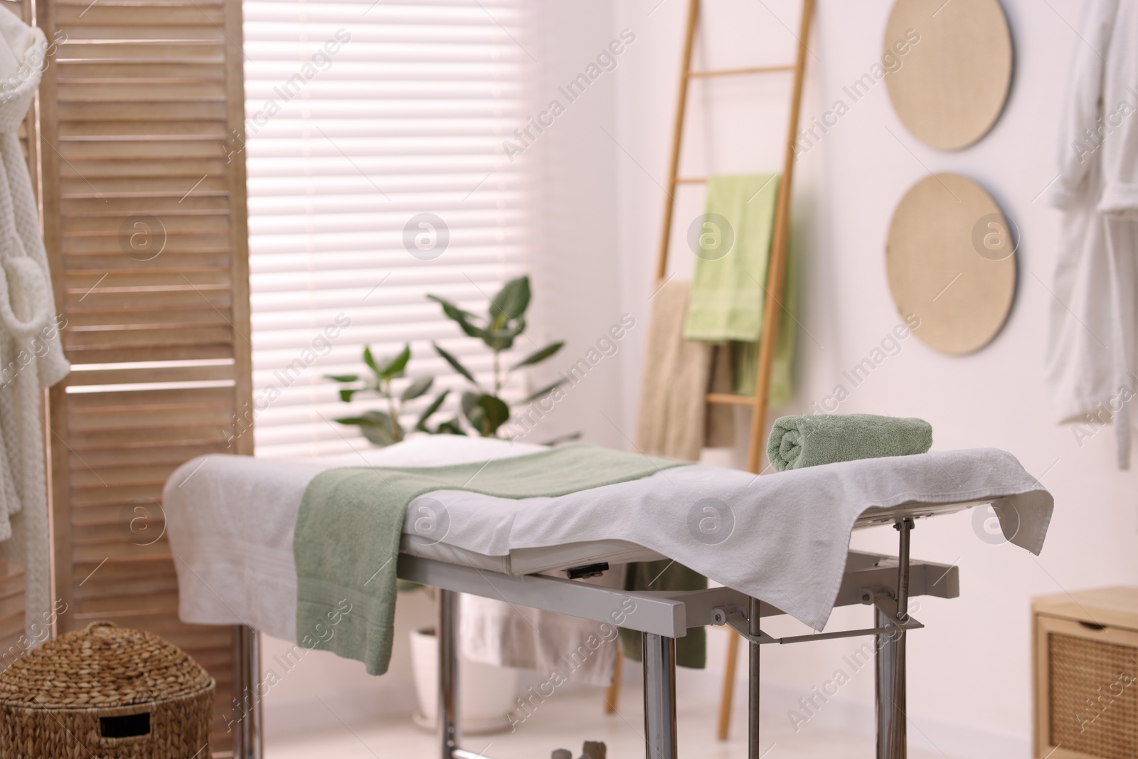 Photo of Comfortable massage table with clean towels in spa center