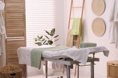 Comfortable massage table with clean towels in spa center