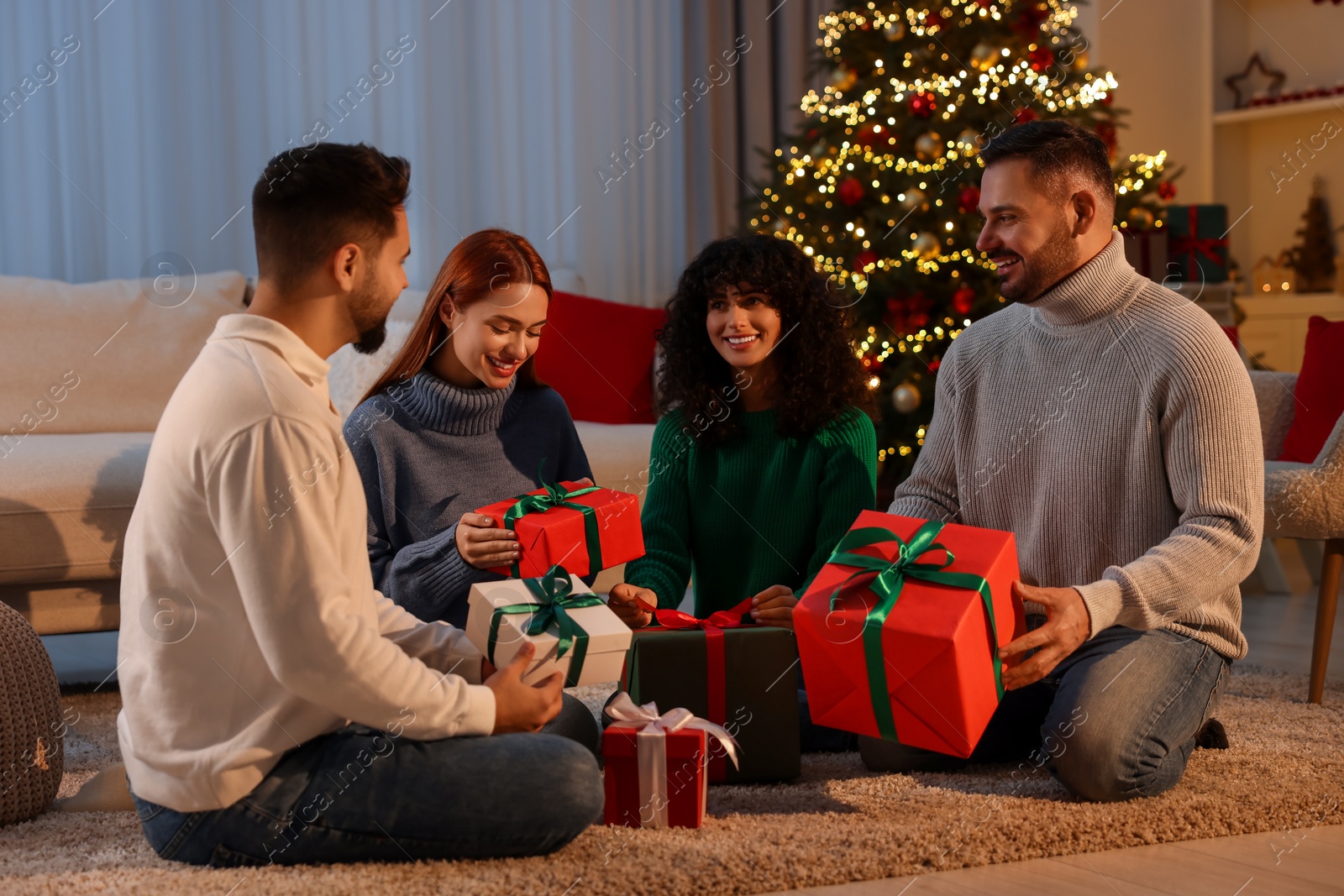 Photo of Christmas celebration. Happy friends exchanging gifts at home