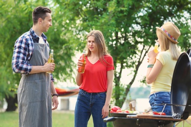 Photo of Young people having barbecue with modern grill outdoors