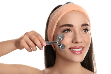 Woman using metal face roller on white background