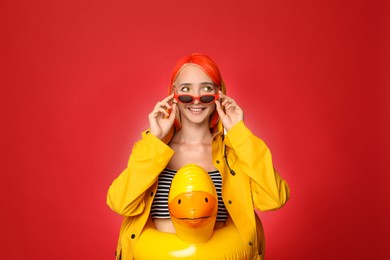 Photo of Beautiful young woman with bright dyed hair and inflatable ring on color background