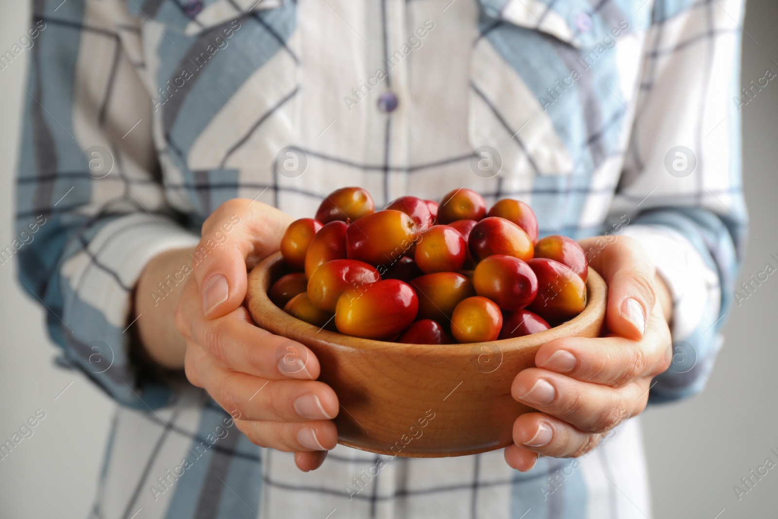 Photo of Woman holding bowl with palm oil fruits, closeup