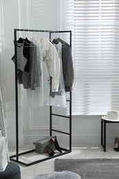 Photo of Rack with stylish women's clothes in dressing room. Interior design